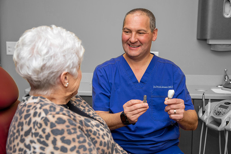 dr avason consulting with elderly patient and showing her dental implant components