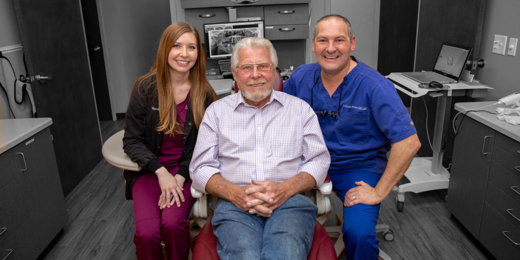 dr avason and hygienist with white haired gentleman smiling after dental implants procedure