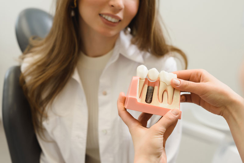 Dental Patient Getting Shown A Dental Implant Model During Her Consultation in Denver, NC