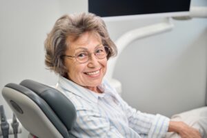 A concerned-looking woman is sitting in a dentist's chair while the dentist shows her an insurance form. The dentist is pointing at the annual maximums and deductibles on the form to help her understand the costs. No text on image.