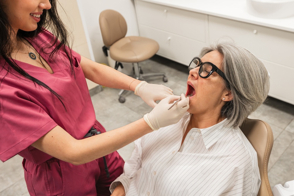 A close up image showcasing the dental implant procedure, with a focus on the dental implant being placed in the patient's jawbone. No text on the image.