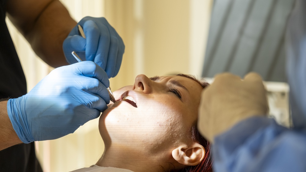 Worried patient in a dental chair, looking concerned as a dentist points to a digital scan of their teeth on a monitor. The text overlay says "I Need My Teeth Fixed: What Are My Options?"