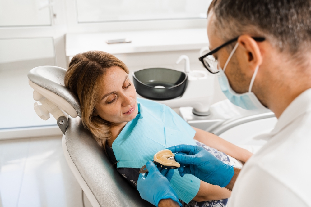Dentist showing a dental restoration plan to a patient in a modern office.